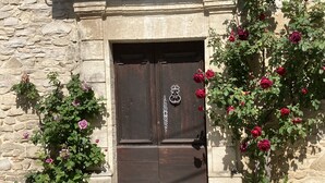 Un bâtiment en pierre avec une porte en bois sombre, un heurtoir en métal et un mur en pierre.