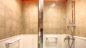 A glass-enclosed shower with a handheld showerhead and a handheld faucet.