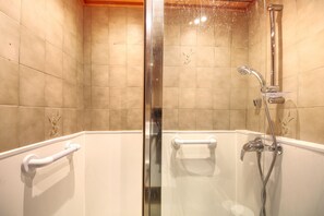 Ducha con cerramiento de vidrio, cabezal de ducha manual y grifo de mano.