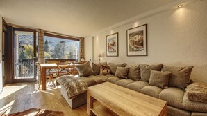A modern living room with a large sectional sofa, a wooden coffee table, and a dining area with a table and chairs.