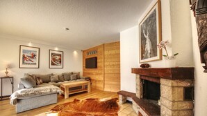 A cozy living room with a sofa, a fireplace, and wooden paneling.