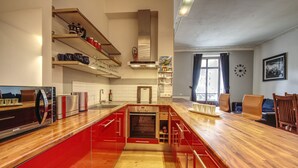 A modern kitchen with red cabinetry, a built-in oven, and a wooden countertop.