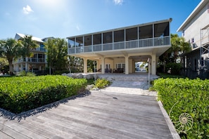 Una casa moderna con un espacio exterior cubierto, una terraza de madera y jardines bien cuidados.