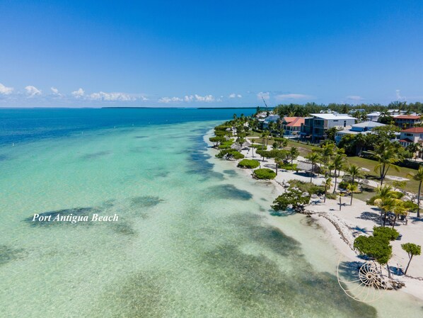 Enjoy stunning views of Port Antigua Beach from our resort, surrounded by palm trees and thatched-roof structures.