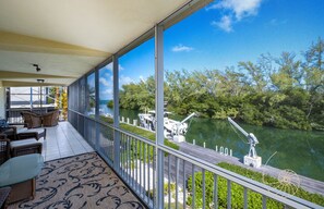 Enjoy the serene river views from this balcony, featuring wicker furniture and a patterned rug.