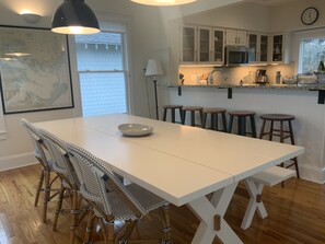 Una cucina moderna con mobili bianchi, una grande isola con sgabelli, una mappa appesa al muro e un orologio a parete.