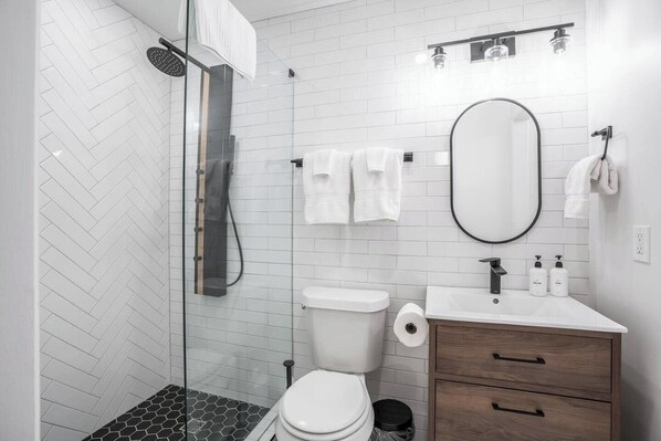 A modern bathroom with a shower, toilet, and vanity.