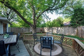 A wooden deck with a round table and chairs, surrounded by a wooden fence and trees. - East Side Emerald - Incredible Location!  Pool Table, Fire Pit, 2K (Wichita)