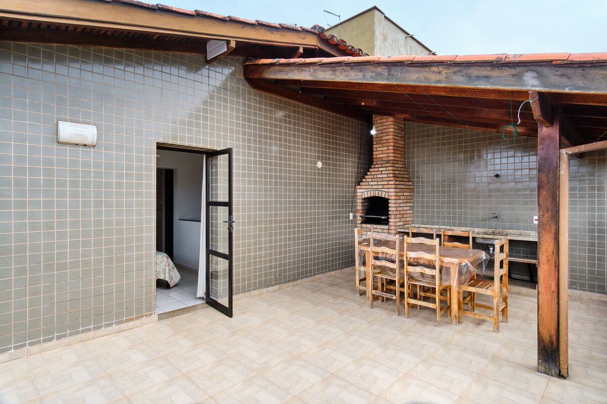 Un patio con un horno de ladrillo, paredes de azulejos y una mesa y sillas de madera.