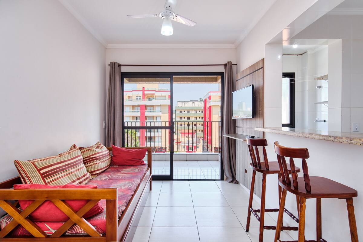 Una habitación con cama, televisor, balcón y zona de comedor.
