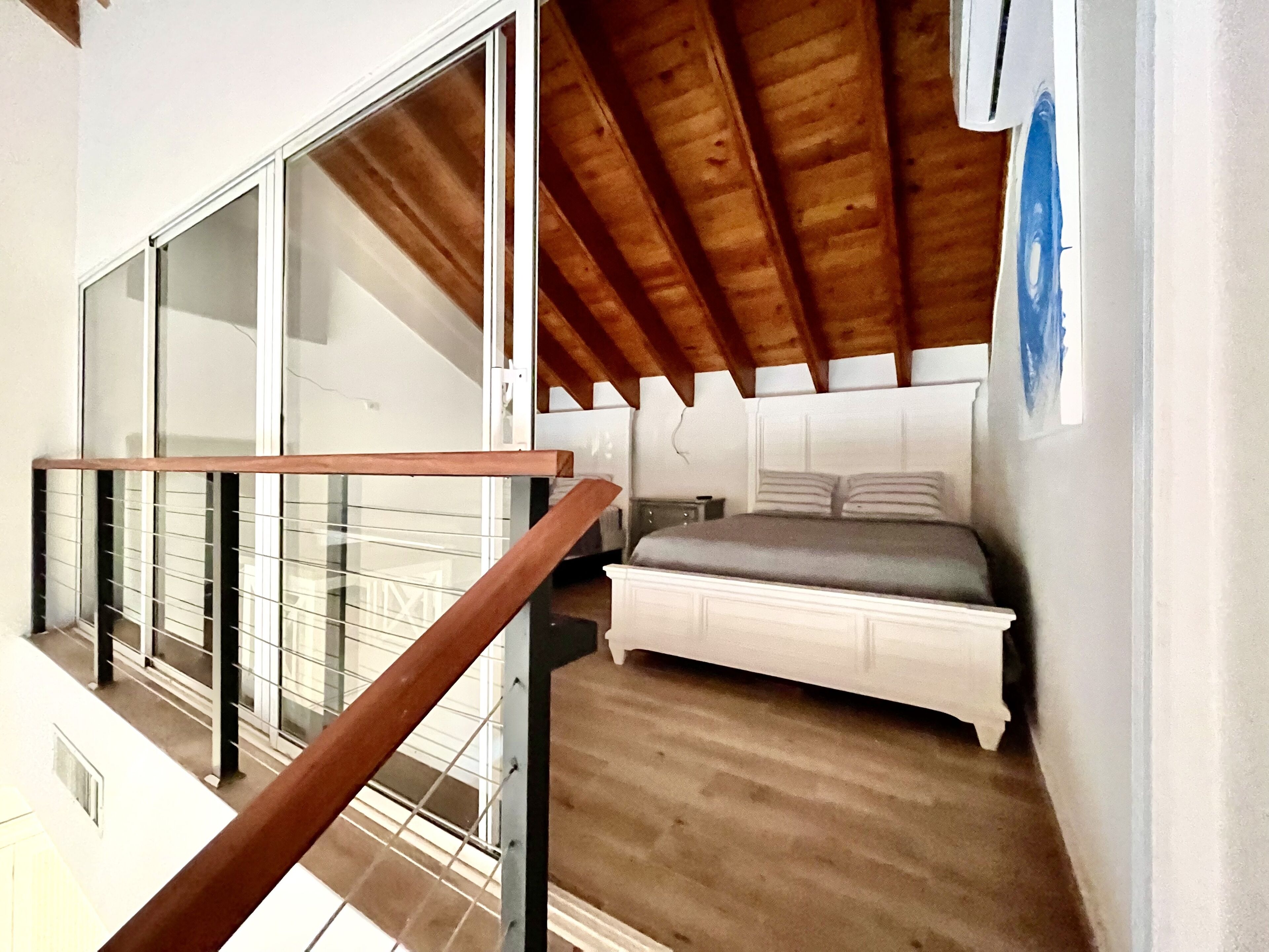 Ein Schlafzimmer mit Holzboden, einem Bett und einem Fenster.