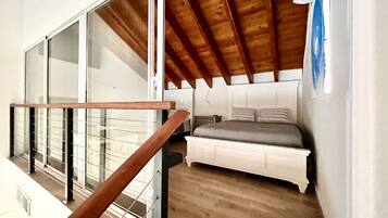 Ein Schlafzimmer mit Holzboden, einem Bett und einem Fenster.