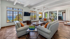 A spacious living room with a large TV, comfortable seating, and a view of the ocean. - Tranquilo/Stunning Sanctuary (Rincon)