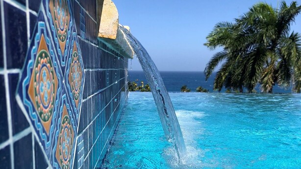 A pool with clear blue water and a tiled wall with a geometric pattern. - Tranquilo/Stunning Sanctuary (Rincon)
