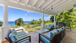 A covered outdoor seating area with wicker furniture and a view of the ocean. - Tranquilo/Stunning Sanctuary (Rincon)