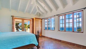A bedroom with a bed, large windows, and a view of the sea. - Tranquilo/Stunning Sanctuary (Rincon)