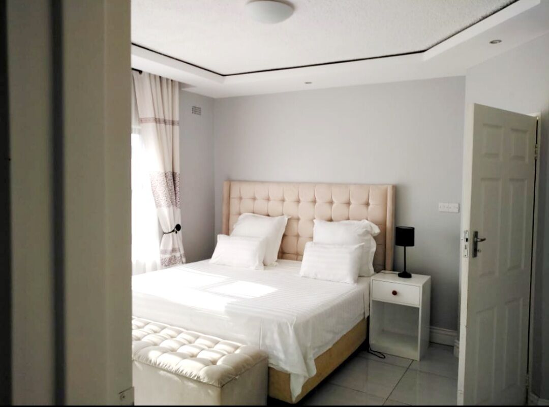 Een slaapkamer met een groot bed, een nachtkastje en een bijzettafeltje.