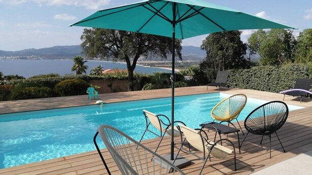 A pool area with a wooden deck, a turquoise umbrella, and lounge chairs. - Comfortable villa overlooking the Gulf of Ajaccio  (Grosseto-Prugna)
