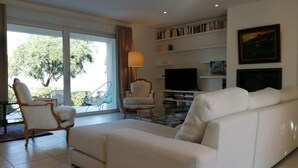 A spacious living room with a white sofa, a television, and a bookshelf. - Comfortable villa overlooking the Gulf of Ajaccio  (Grosseto-Prugna)