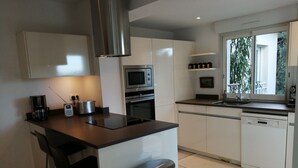 A modern kitchen with a central island, stainless steel appliances, and a window providing natural light. - Comfortable villa overlooking the Gulf of Ajaccio  (Grosseto-Prugna)