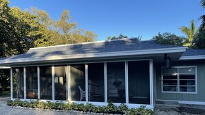 A house with a covered porch, large windows, and a gravel driveway. - Flip Flop 2 (Sanibel)