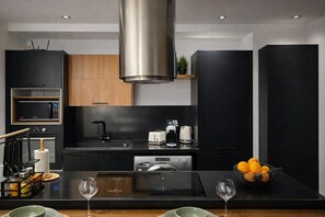 A modern kitchen with a central island, built-in appliances, and a black and wood color scheme. - Captivating 2-bed Apartment in Tunis (Tunis)