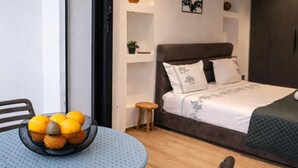 A bedroom with a bed, a small stool, a round table with a fruit bowl, and a chair. - Captivating 2-bed Apartment in Tunis (Tunis)