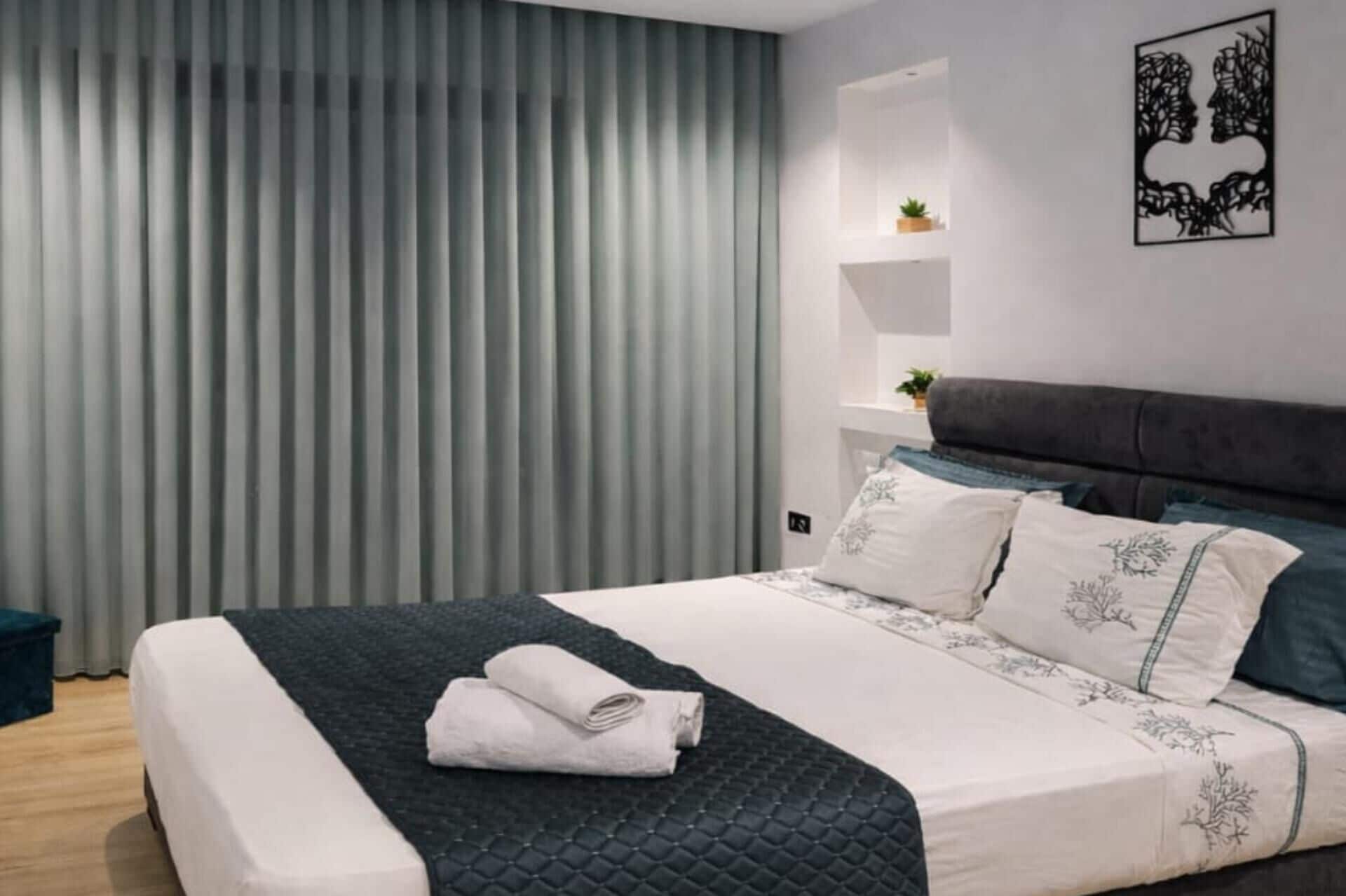 Un dormitorio moderno con una cama, una mesita de noche con una planta y un estante en la pared.