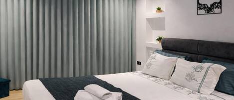 Un dormitorio moderno con una cama, una mesita de noche con una planta y un estante en la pared.