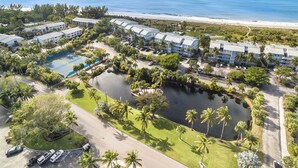An aerial view of a resort with multiple buildings, a tennis court, a swimming pool, and a lake. - South Seas Beach Villa 2414 (Captiva)