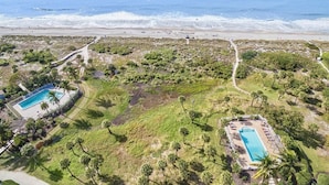 An aerial view of a coastal property with two swimming pools, a beach, and a path leading to the beach. - South Seas Beach Villa 2414 (Captiva)