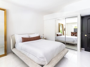 A modern bedroom with a bed, bedside table, and a large mirror.