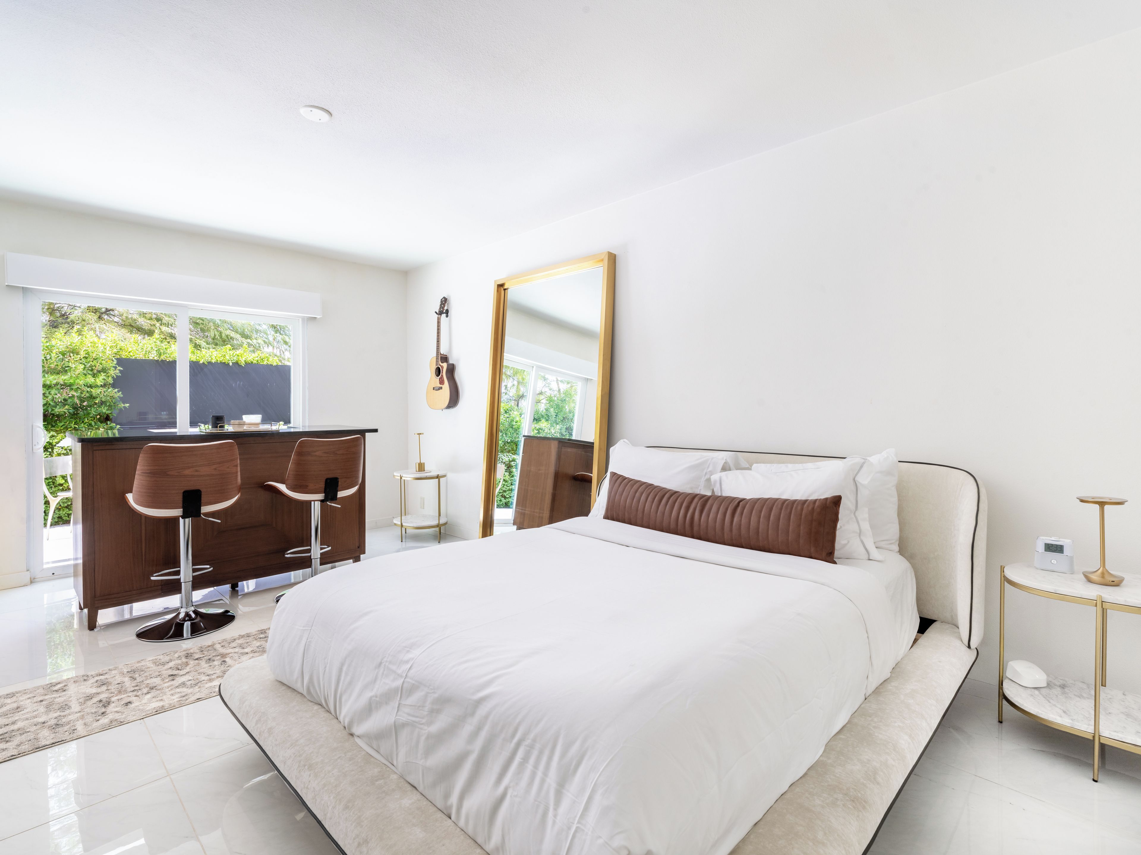A modern bedroom with a large bed, a desk, and a mirror.