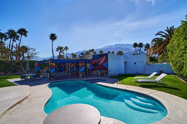A swimming pool with a mural, lounge chairs, and palm trees. - Family Luxury, Mountain views, Pool/Hot Tub, (Palm Springs)