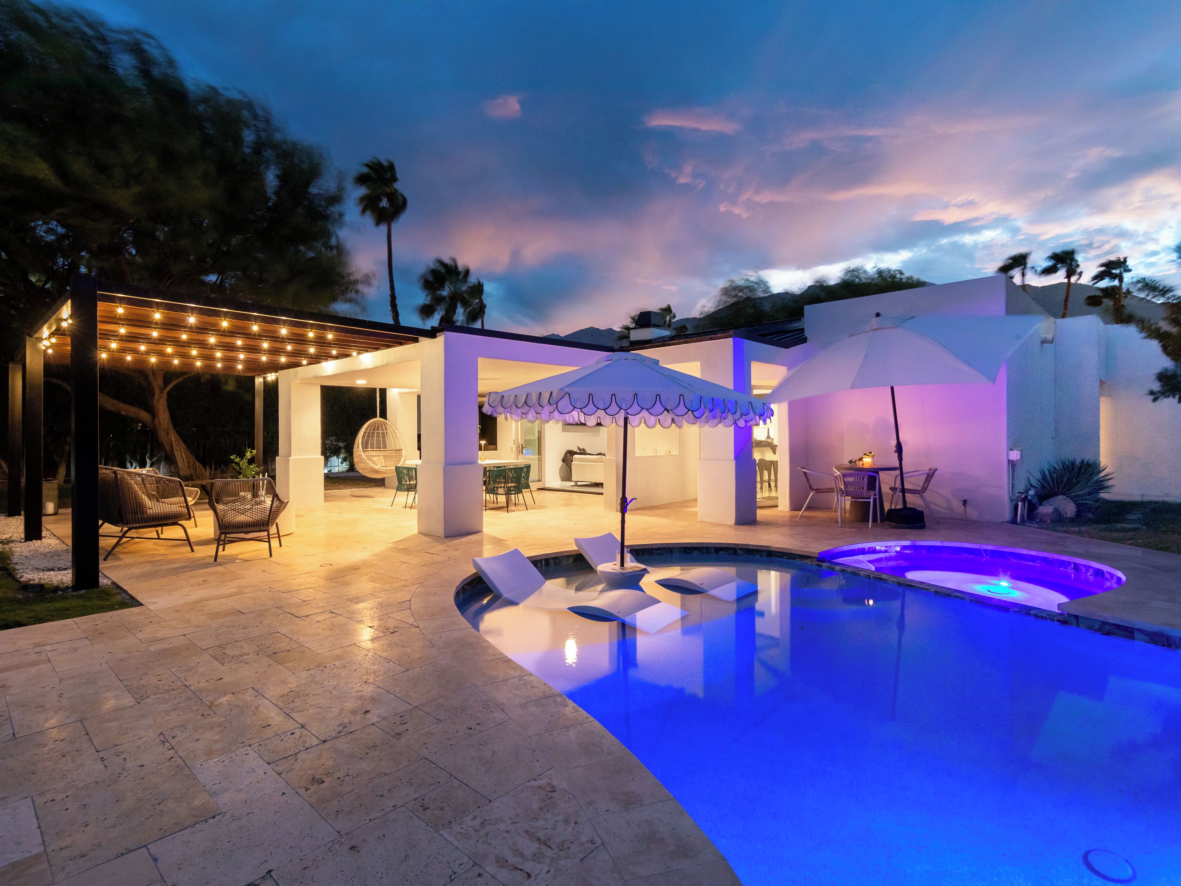 A modern outdoor pool area with a covered seating area and a patio.