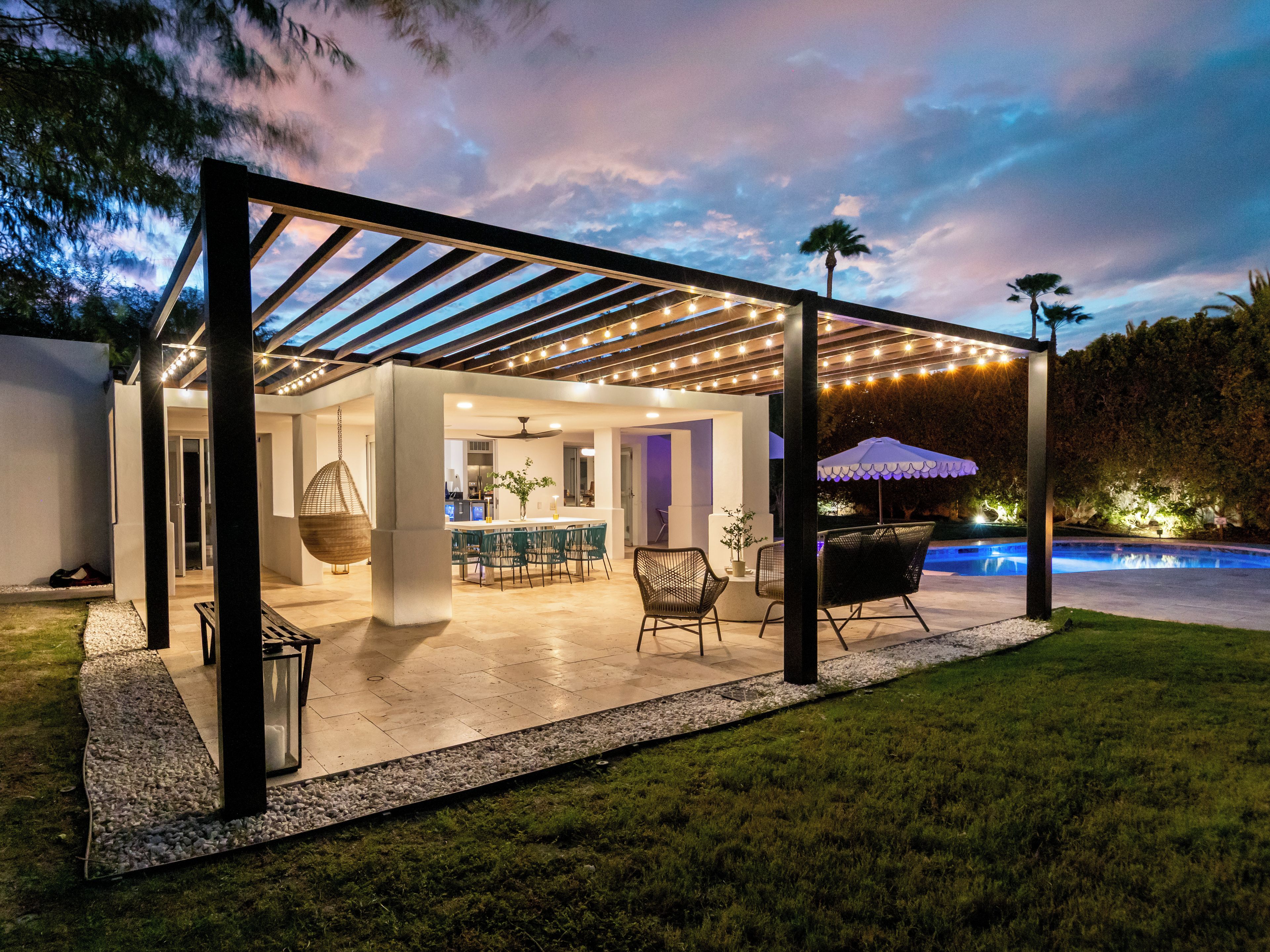 A covered outdoor patio with a pool, seating area, and a bar.
