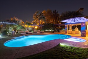 A nighttime swimming pool with a lounge area, umbrellas, and a covered seating area. - Family Luxury, Mountain views, Pool/Hot Tub, (Palm Springs)