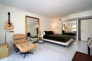 A modern bedroom with a bed, a chair, a desk, a lamp, a guitar, and a large mirror. - Family Luxury, Mountain views, Pool/Hot Tub, (Palm Springs)
