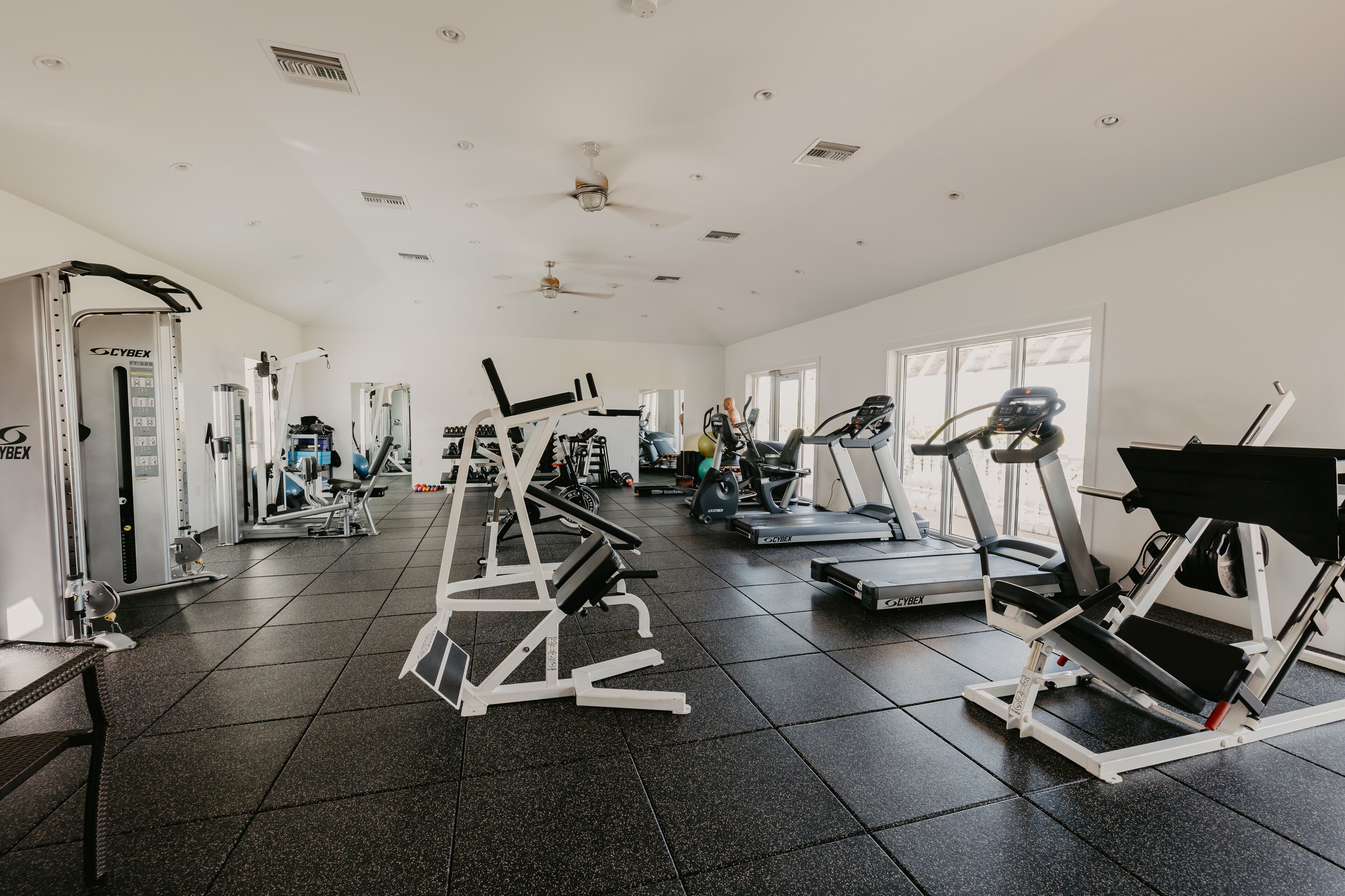 Un gimnasio con varios equipos de ejercicio, incluyendo cintas de correr y máquinas de pesas.