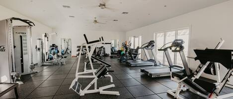 Un gimnasio con varios equipos de ejercicio, incluyendo cintas de correr y máquinas de pesas.