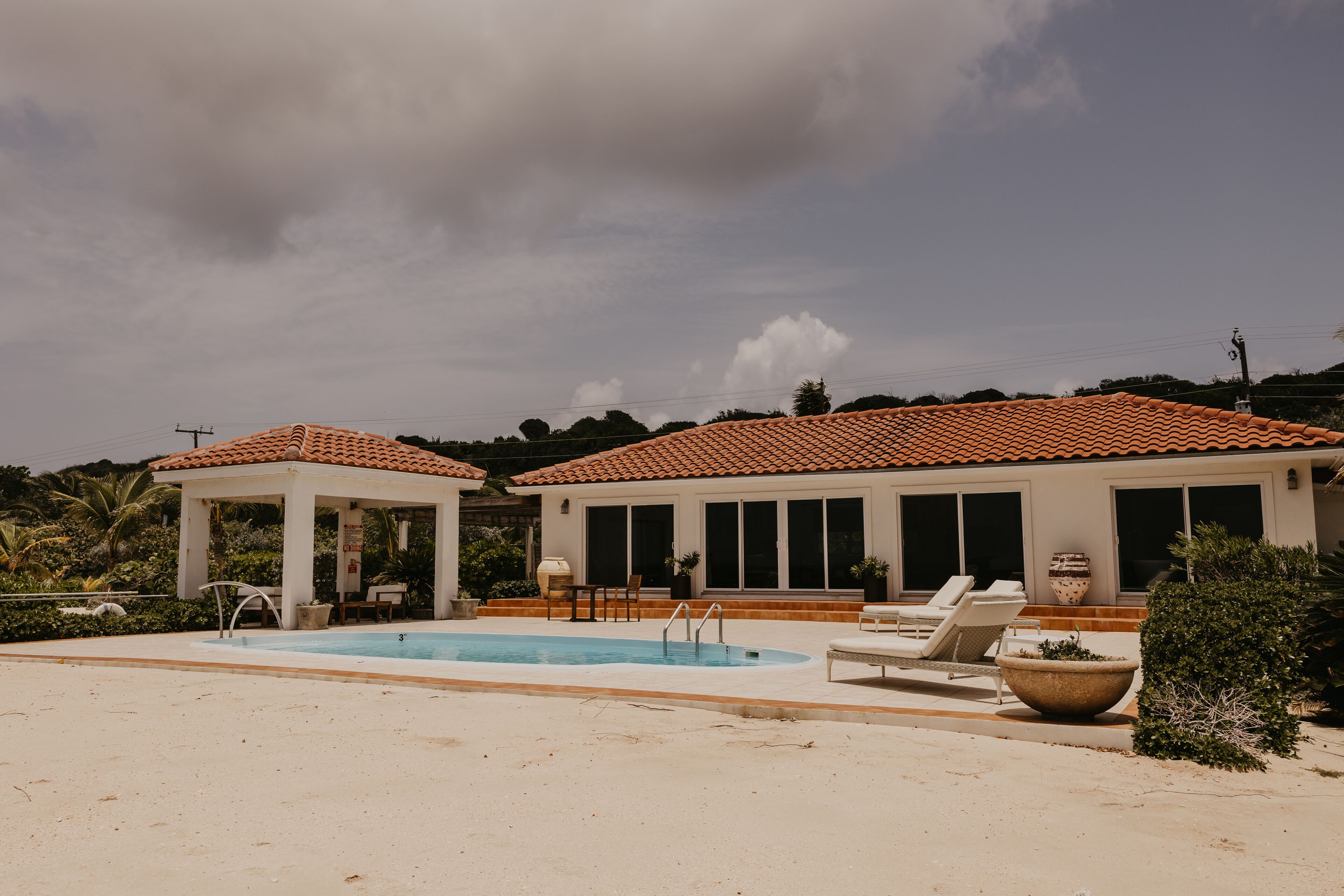 A pool area with lounge chairs and a gazebo.