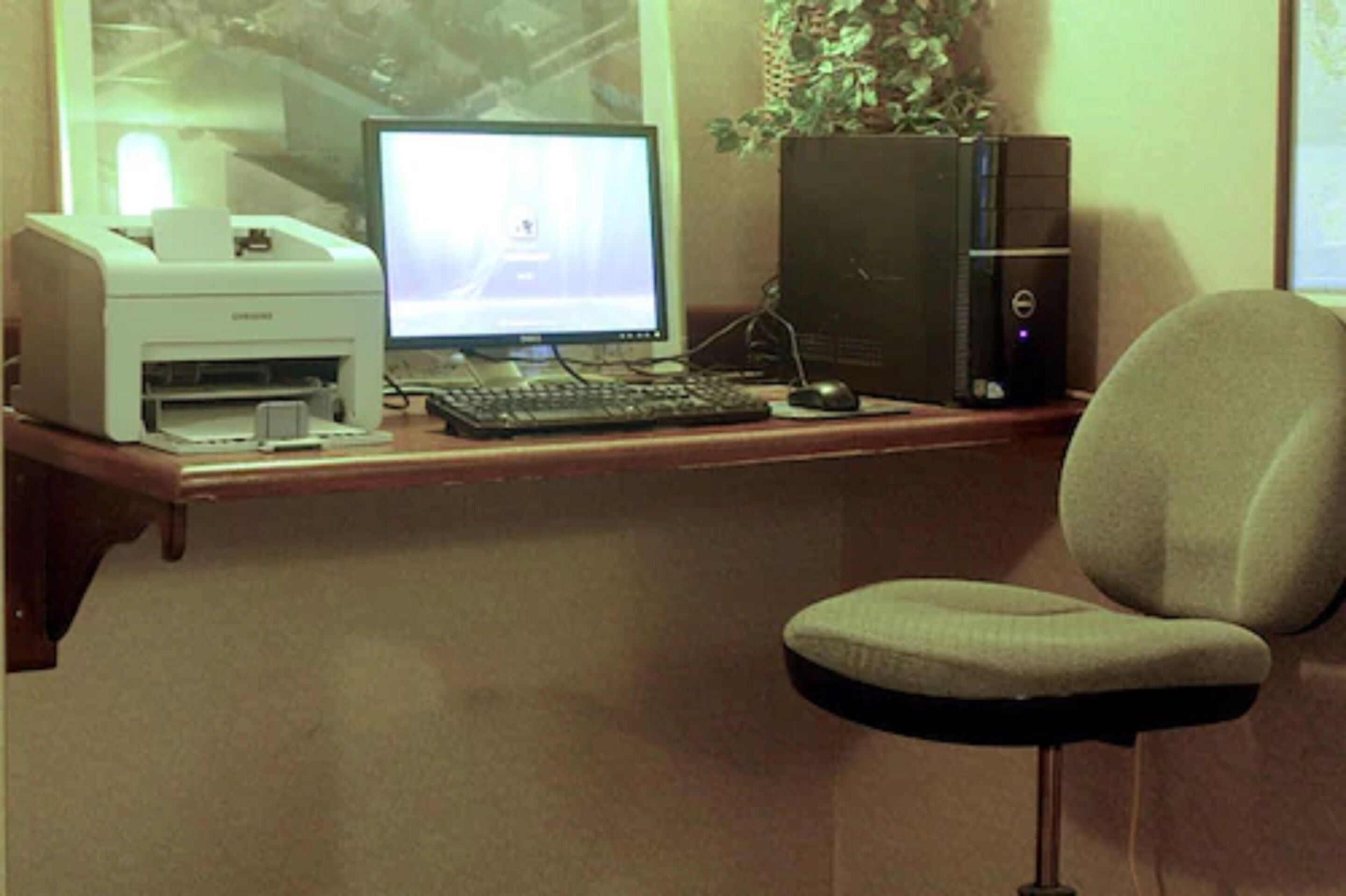 Un espacio de trabajo en casa con una computadora de escritorio, monitor, teclado, ratón e impresora sobre un escritorio.
