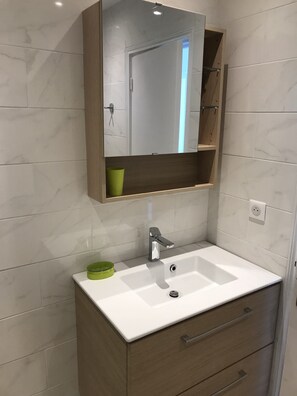 A bathroom with a white sink, a mirror, and a wooden cabinet below. - Apartment 300 meters from the beach in Cannes (Cannes)