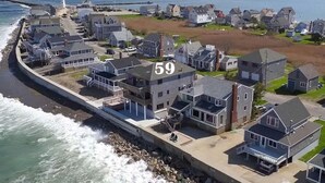 A coastal residential area with houses numbered 59, a lighthouse in the background, and a view of the sea. - Scituate-Weddings, Family Gatherings, Pet Friendly (Scituate)