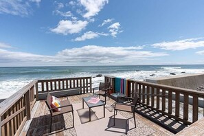 Una terraza de madera con mobiliario exterior con vistas al océano.