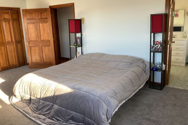 Un dormitorio con una cama grande, puertas de madera, una mesita de noche y un aparador.