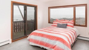 A bedroom with a large bed, a sliding glass door, and a window with a view of the ocean. - Scituate-Weddings, Family Gatherings, Pet Friendly (Scituate)