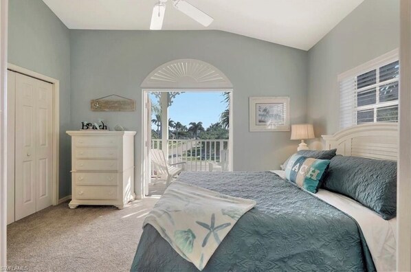 A bedroom with a bed, dresser, and a view of the outdoors.