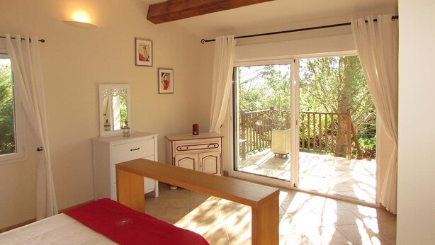 A bedroom with a bed, a desk, a dresser, and a balcony with a wooden railing. - Barjac Villa Pastis - Self-catering cottage with swimming pool and view of the Cevennes mountains (Barjac)