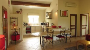 A spacious kitchen with a large island, wooden beams, and a window providing natural light. - Barjac Villa Pastis - Self-catering cottage with swimming pool and view of the Cevennes mountains (Barjac)